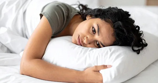 woman staring off with head on pillow in bed