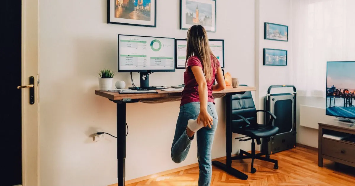 Girl standing and stretching her quad at work computer.